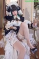 A woman in a maid outfit sitting on a chair.