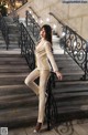 A woman in a beige suit standing on a set of stairs.