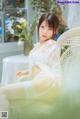 A woman in a white lingerie sitting on a chair.