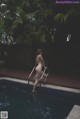 A naked woman standing on the edge of a swimming pool.