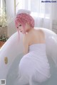 A woman with pink hair sitting in a bathtub.