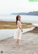 A woman in a white dress standing on a beach.