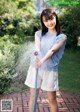 A young woman is holding a hose and spraying water.