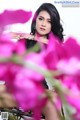 A woman sitting on a chair surrounded by pink flowers.