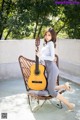 A woman sitting on a chair holding a guitar.