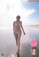 A woman in a bikini walking on the beach.