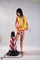 A woman in a safety vest holding a chainsaw next to a traffic cone.