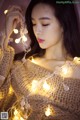 A woman in a sweater holding a string of lights.