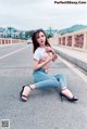 A woman sitting on the side of a road with her legs crossed.