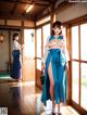 A woman in a blue kimono standing in a room.