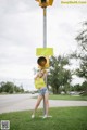 A woman standing next to a traffic light on a pole.