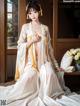 A woman in a white and yellow kimono sitting on a window sill.