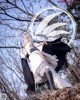 A woman in a white dress and black cape standing in the woods.