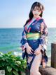 A woman in a kimono posing on a pier by the ocean.