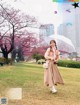 A woman walking in a park holding an umbrella.